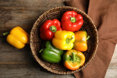 Photo of Bowl with ripe paprika peppers on wooden background, top view