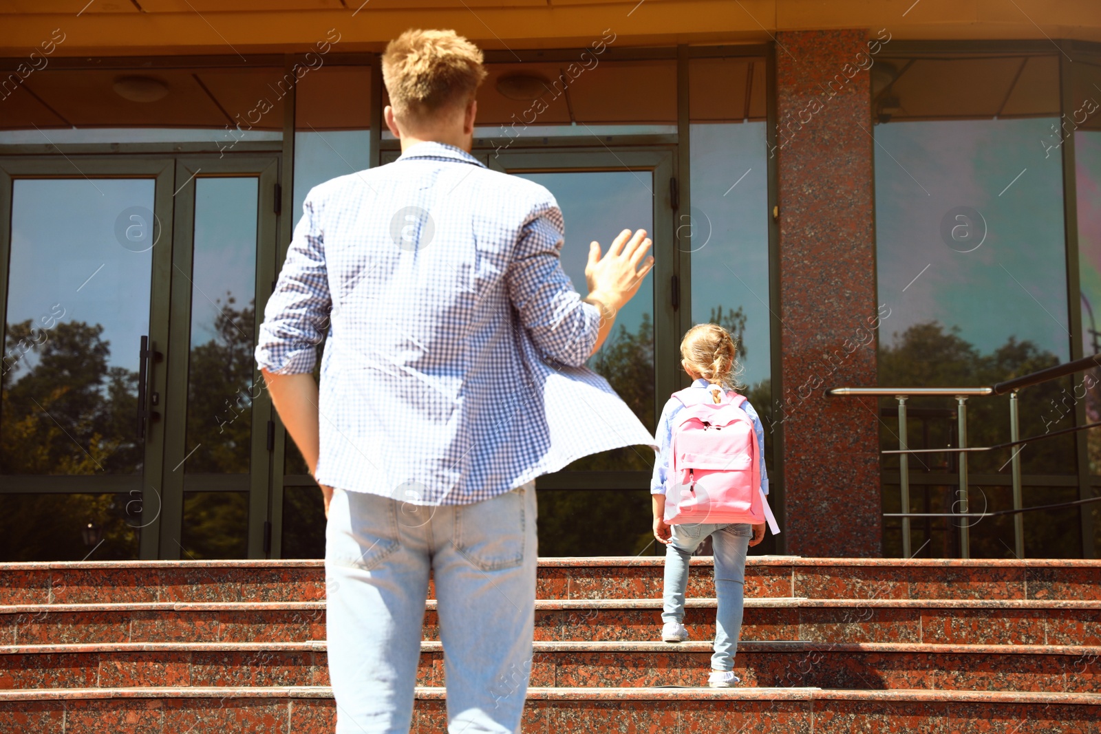 Photo of Young father seeing his little child off to school outdoors