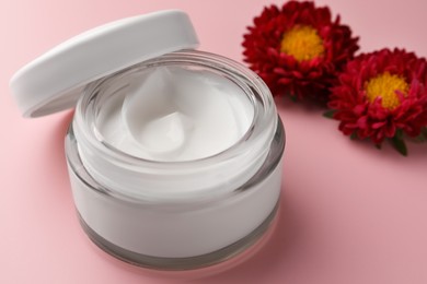 Jar of face cream and chrysanthemum flowers on pink background