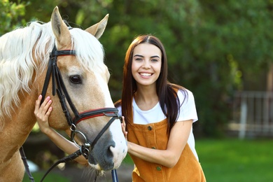 Photo of Palomino horse in bridle and young woman outdoors
