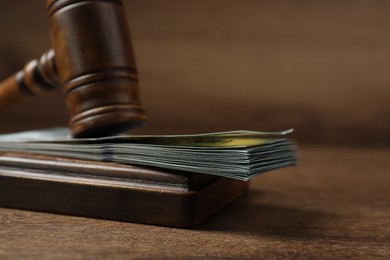 Photo of Law gavel with stack of dollars on wooden table, closeup. Space for text