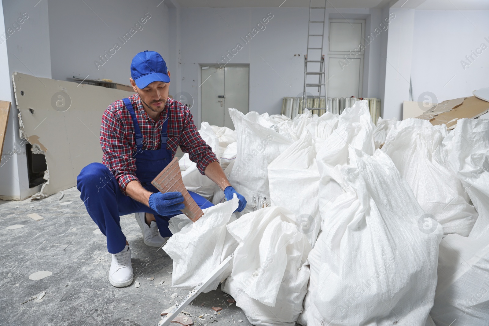 Photo of Construction worker with used building materials in room prepared for renovation