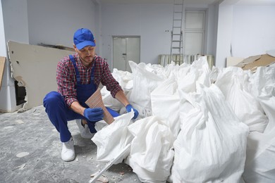 Construction worker with used building materials in room prepared for renovation