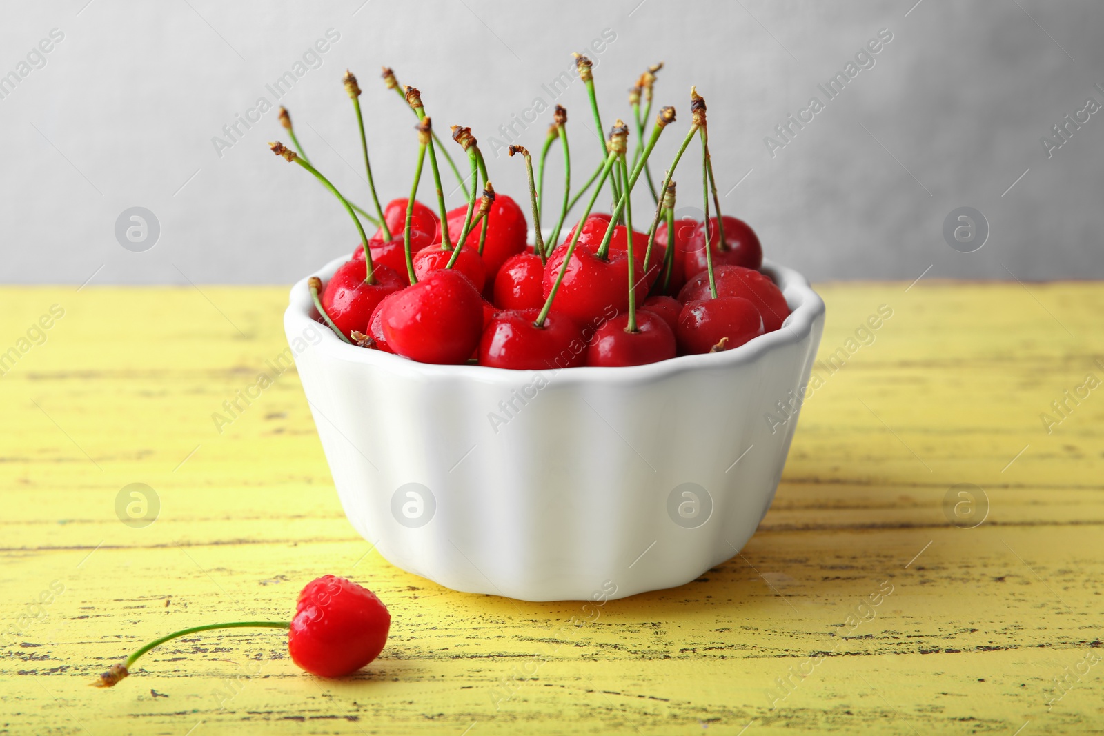 Photo of Bowl with ripe red cherries on wooden table