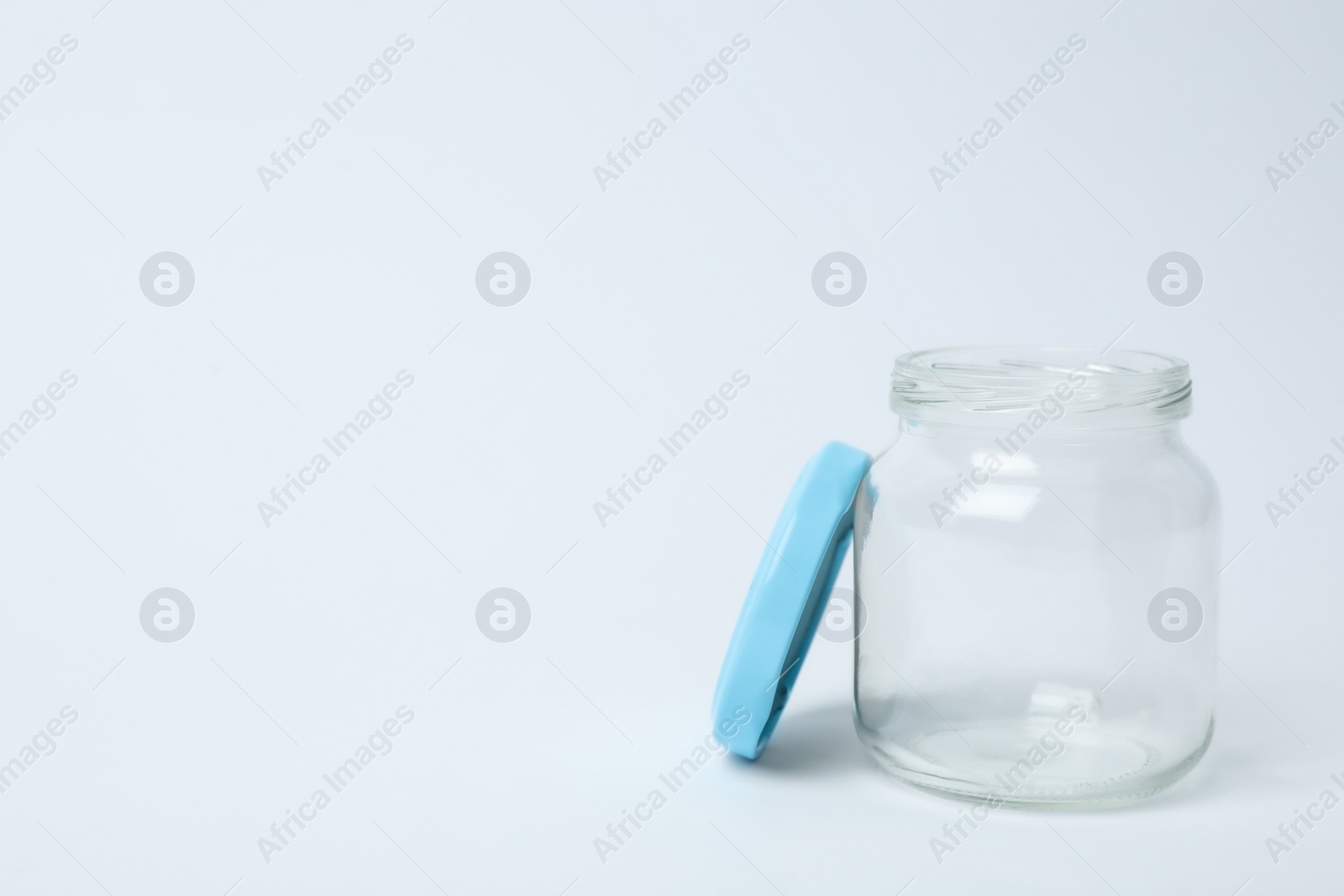 Photo of Open empty glass jar on light background, space for text