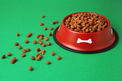 Photo of Dry pet food in feeding bowl on green background