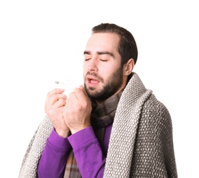 Young man with cold sneezing on white background