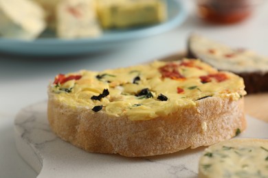 Photo of Tasty butter with olives, chili pepper and bread on table, closeup