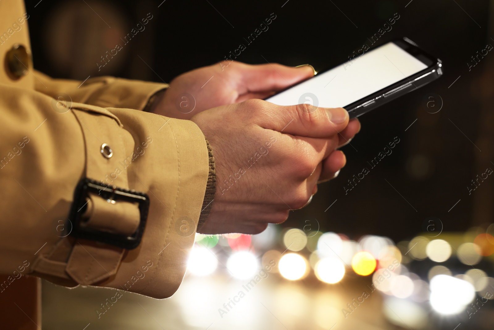 Photo of Man using smartphone on night city street, closeup