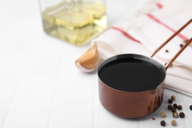 Photo of Metal small saucepan with balsamic vinegar and ingredients on white tiled table. Space for text