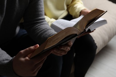 Photo of Couple sitting and reading holy Bibles, closeup