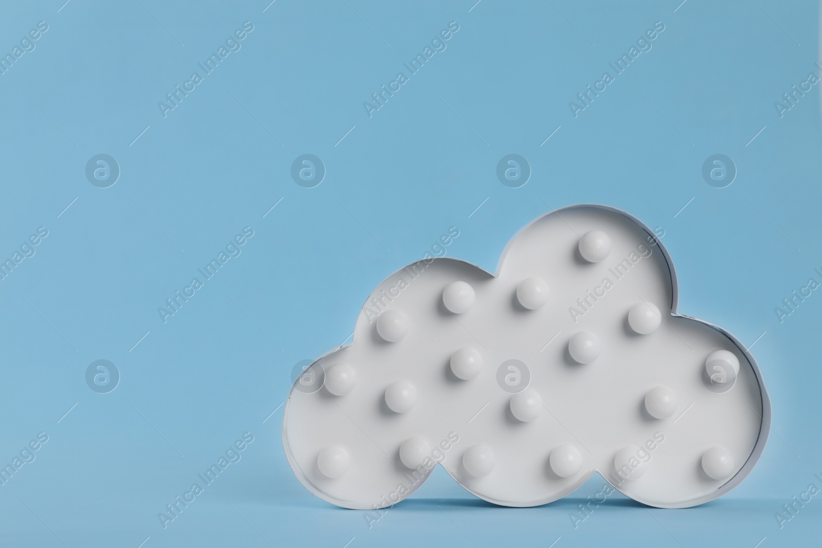 Photo of Stylish cloud shaped night lamp on light blue background. Space for text