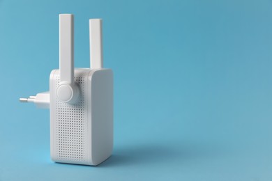 Photo of New modern Wi-Fi repeater on light blue background, space for text