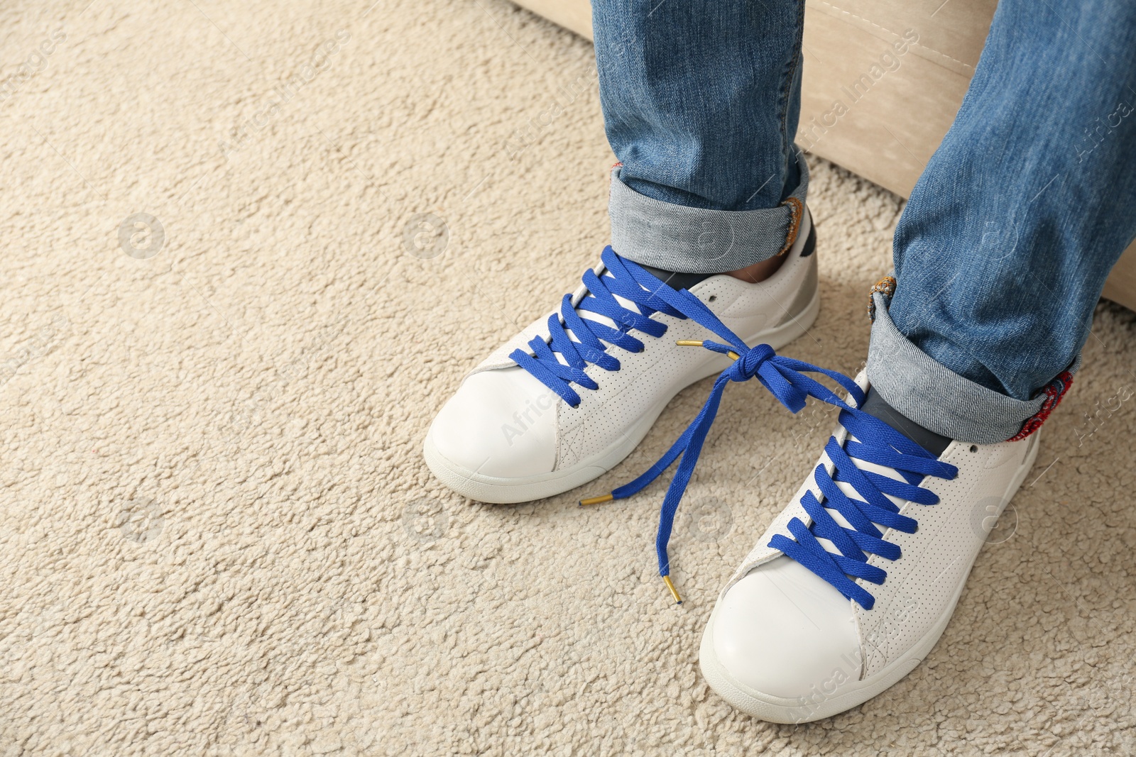 Photo of Man wearing sneakers with tied together laces, closeup. April fool's day