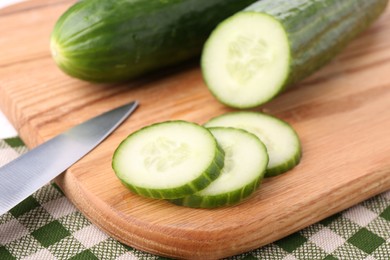 Photo of Cucumbers, knife and cutting board on table, closeup