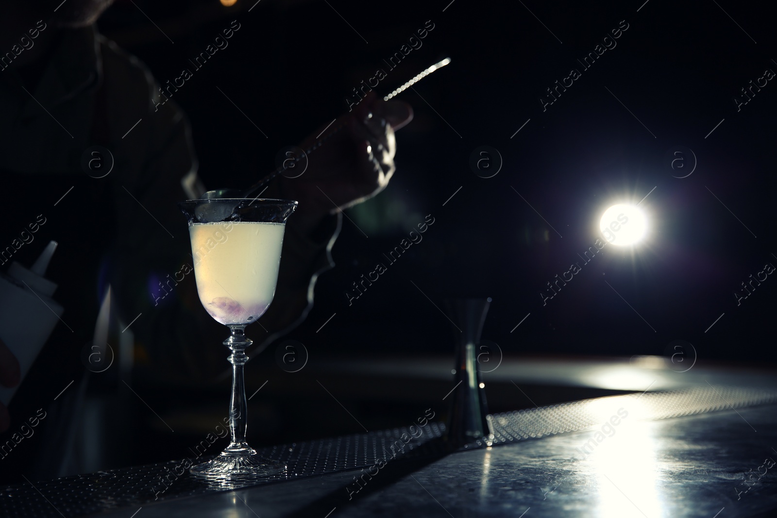 Photo of Barman adding cranberry syrup into cosmopolitan martini cocktail at counter, closeup. Space for text