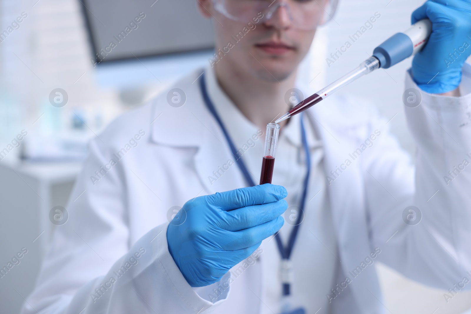 Photo of Scientist dripping sample into test tube in laboratory, closeup