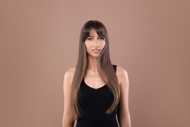 Photo of Hair styling. Portrait of beautiful woman with straight long hair on pale brown background