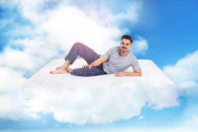 Young man lying on mattress in clouds