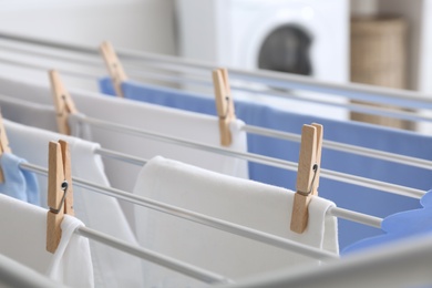 Clean laundry hanging on drying rack indoors, closeup