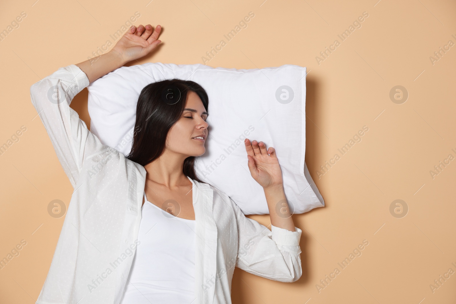 Photo of Young woman sleeping on soft pillow against beige background