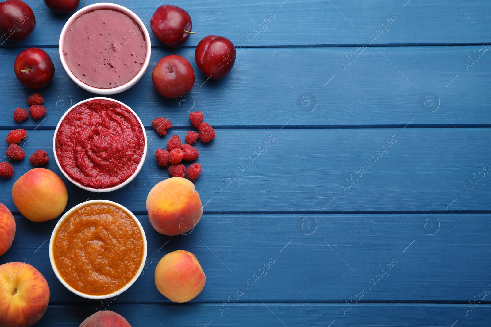 Photo of Different puree in bowls and fresh fruits on blue wooden table, flat lay. Space for text
