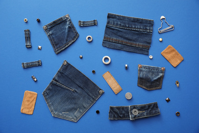 Flat lay composition with garment accessories and cutting details for jeans on blue background