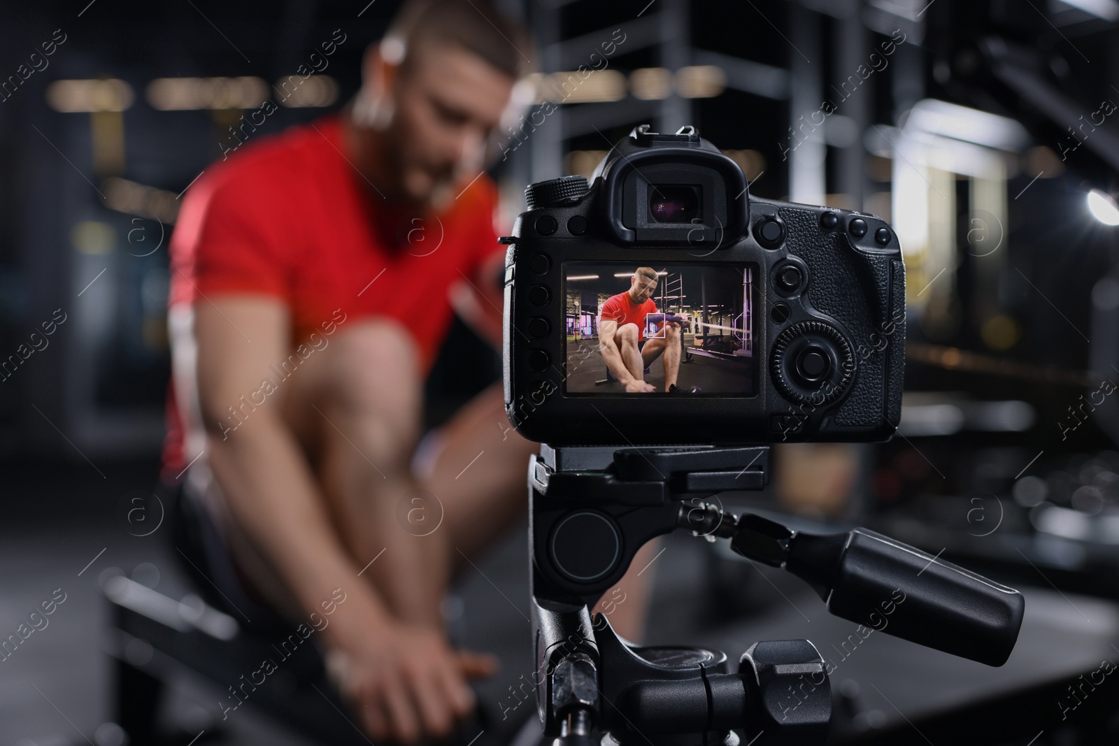 Photo of Man recording workout at gym, focus on camera. Online fitness trainer