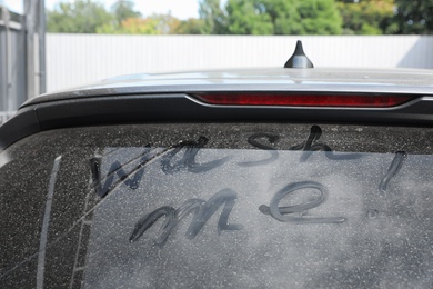 Inscription WASH ME on car window outdoors, closeup