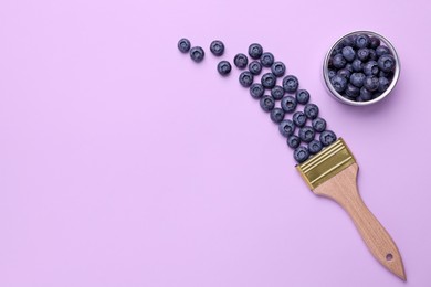 Photo of Creative flat lay composition with paint brush and blueberries on violet background. Space for text