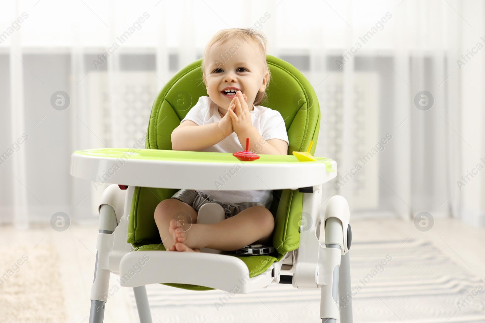 Photo of Children toys. Cute little boy playing with spinning tops in high chair at home