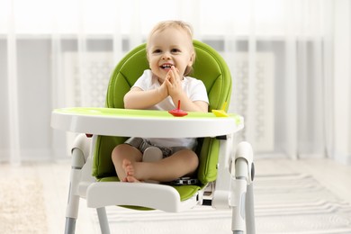 Children toys. Cute little boy playing with spinning tops in high chair at home