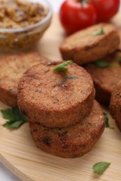 Photo of Tasty vegan cutlets on wooden board, closeup