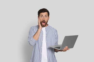Photo of Emotional bearded man with laptop on light background