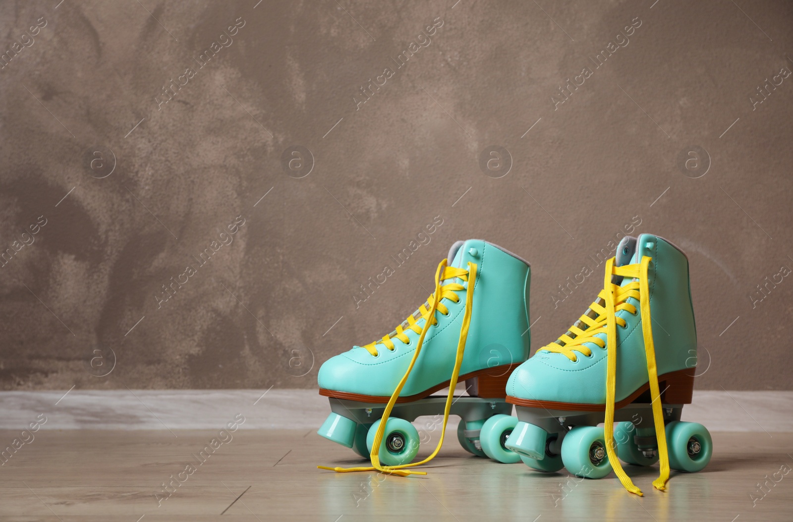 Photo of Vintage roller skates on floor near brown wall. Space for text