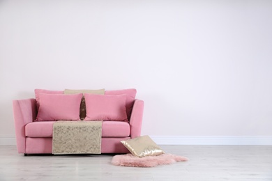 Photo of Stylish pink sofa against white wall in modern living room interior. Space for text