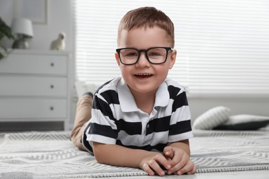 Photo of Cute little boy in glasses on floor at home