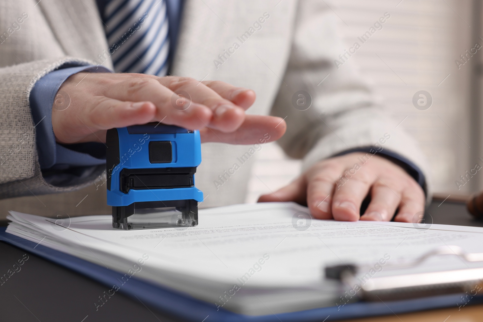 Photo of Notary stamping document at table in office, closeup