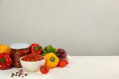 Delicious lecho and fresh ingredients on white wooden table. Space for text