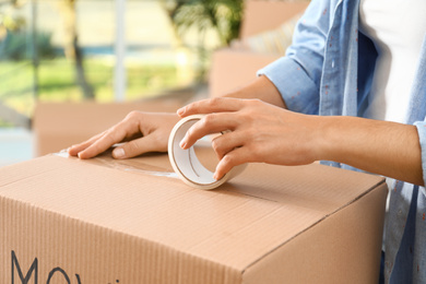 Photo of Woman packing box at table, closeup. Moving day