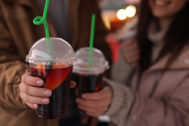 Friends with cups of mulled wine outdoors, closeup