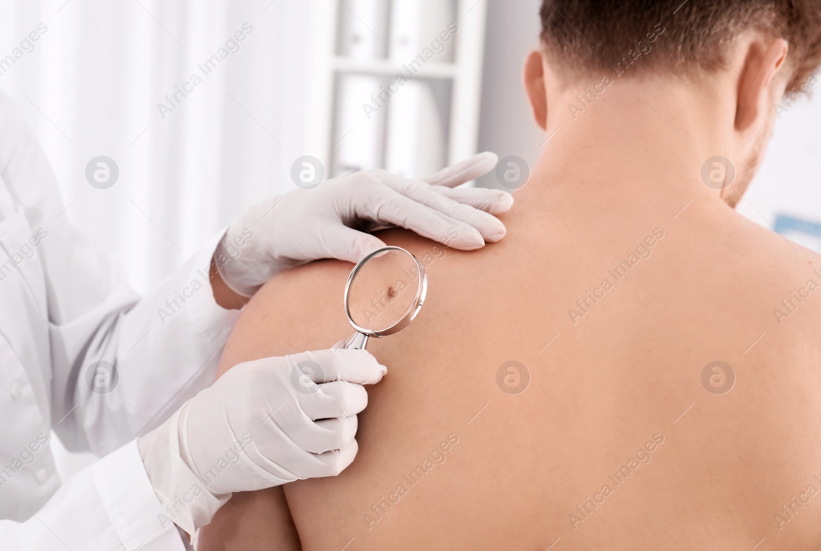 Photo of Dermatologist examining patient with magnifying glass in clinic