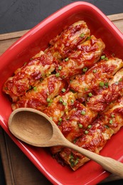 Photo of Delicious stuffed cabbage rolls cooked with homemade tomato sauce on black textured table, top view