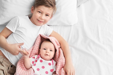 Photo of Cute little baby with elder brother lying on bed at home