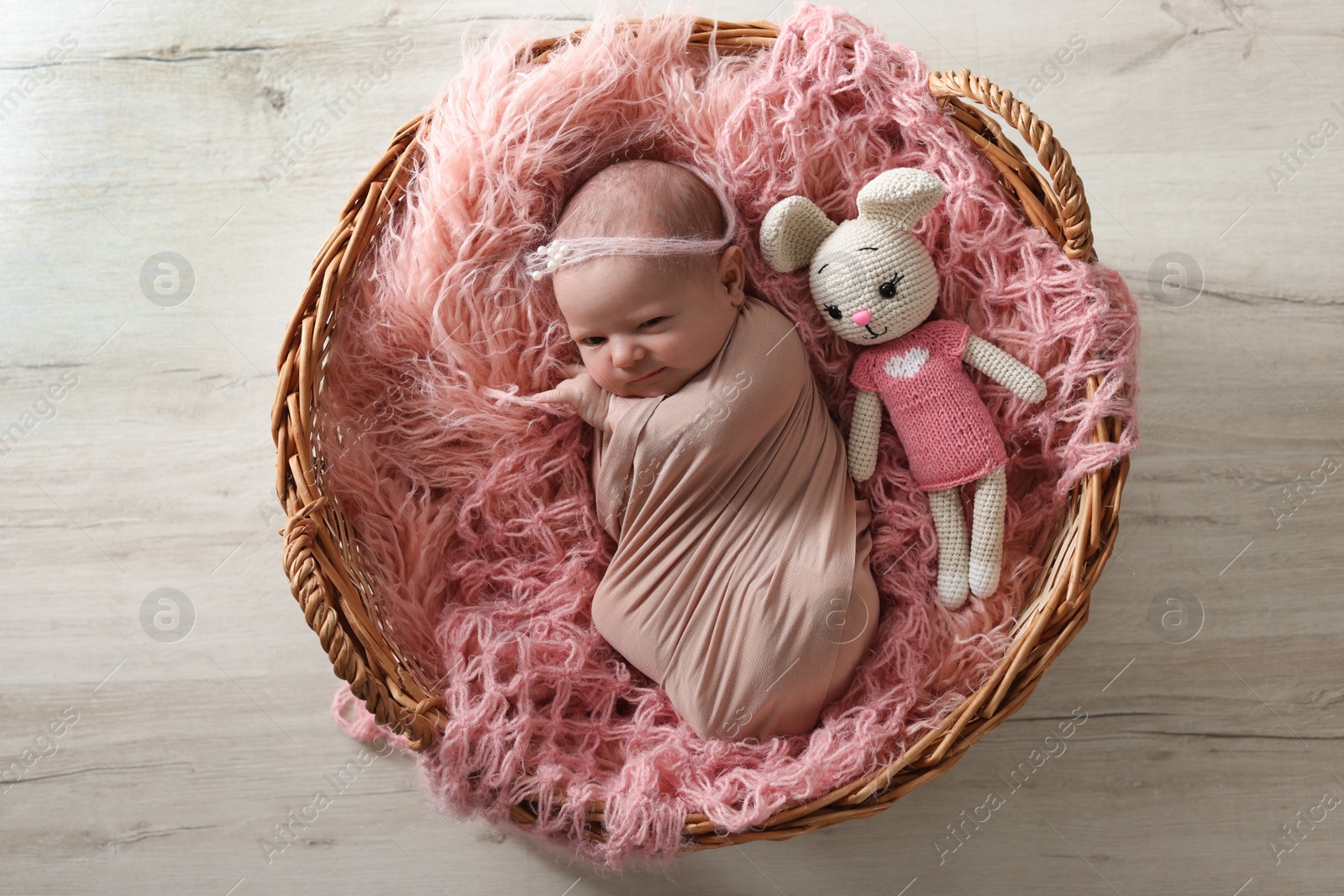 Photo of Adorable little baby wrapped on blanket in wicker basket at home, top view