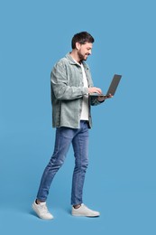 Happy man with laptop on light blue background