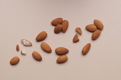 Photo of Delicious raw almonds on beige background, flat lay