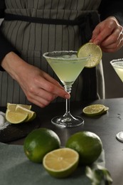 Woman making delicious Margarita cocktail at grey table, closeup