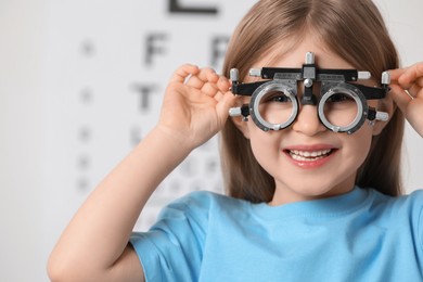 Photo of Little girl with trial frame against vision test chart, closeup