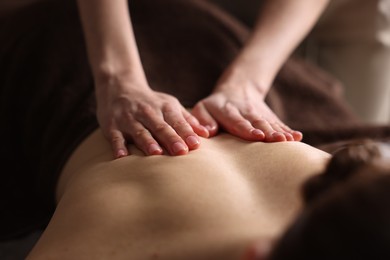 Spa therapy. Beautiful young woman lying on table during massage in salon, closeup